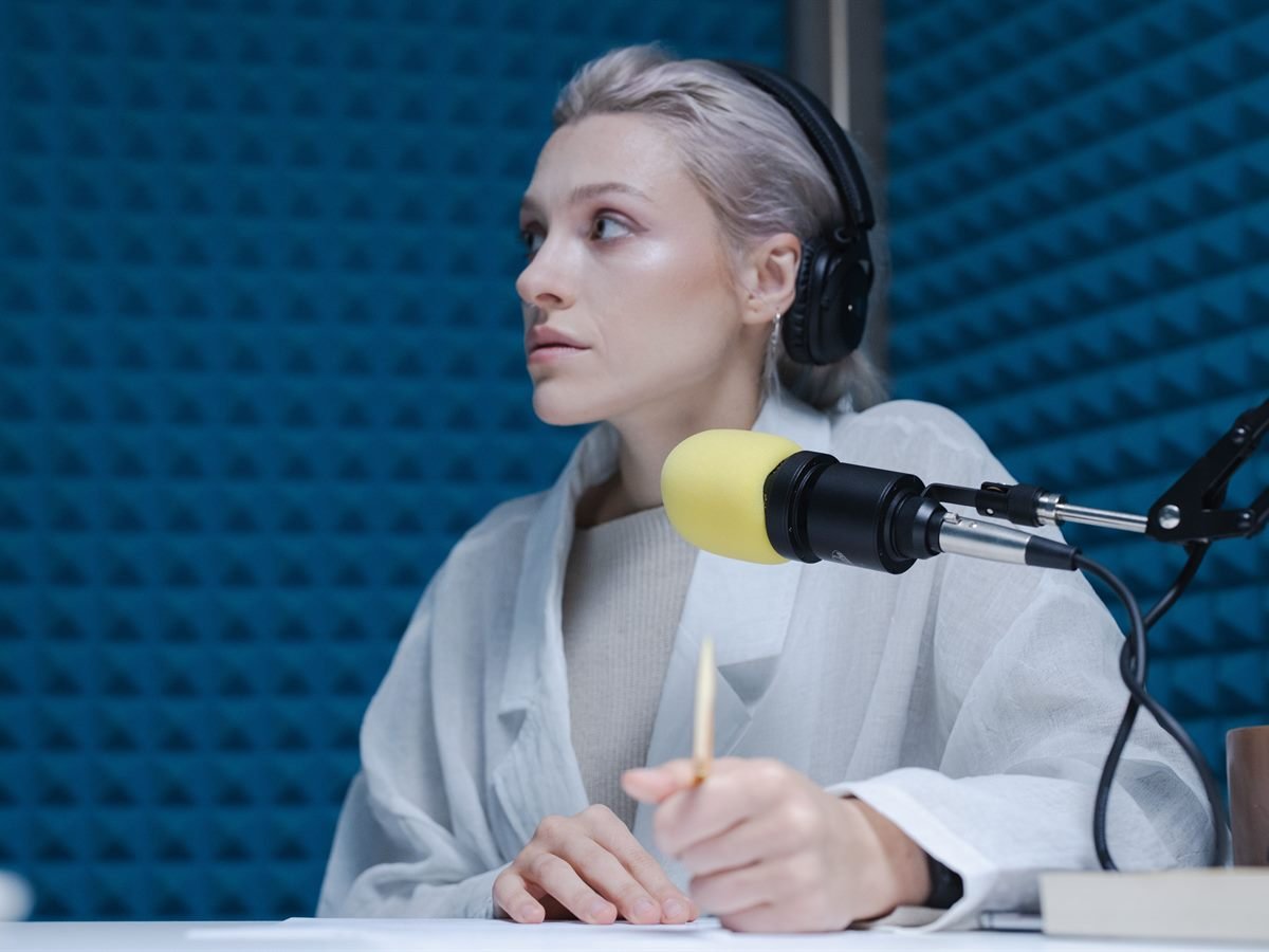 Mujer hablando ante un micrófono en un estudio de grabación