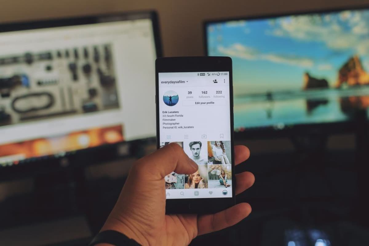 Hand holding a phone showing an Instagram profile